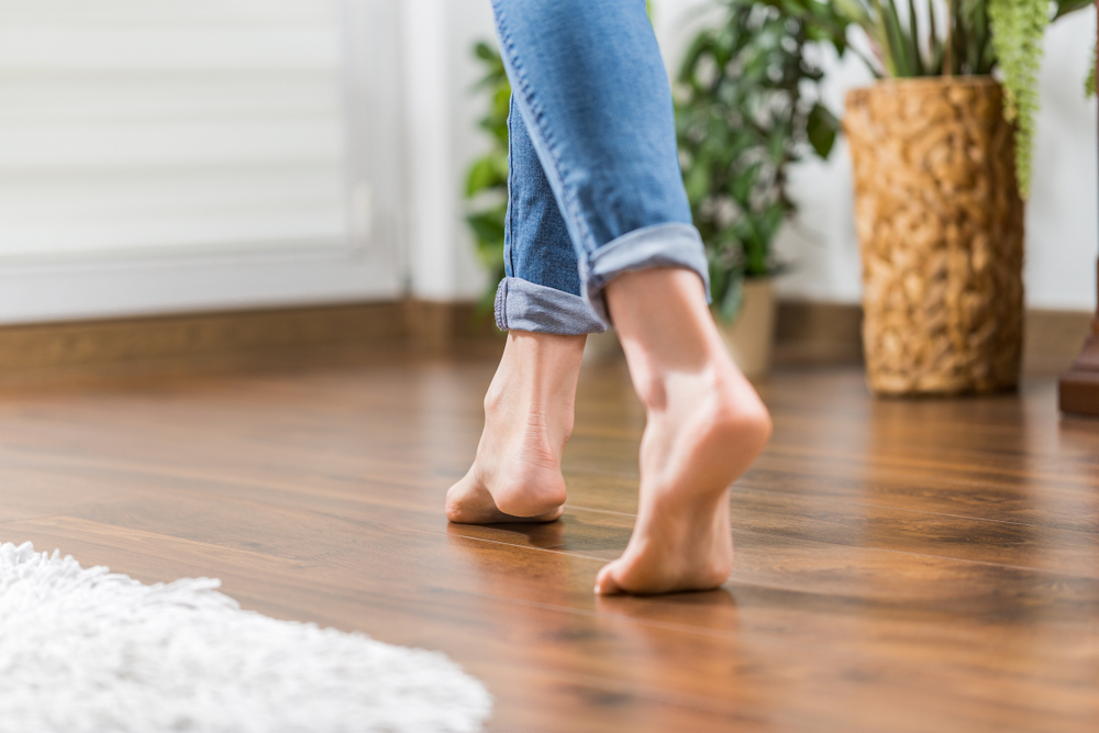A woman in bare feet walking on hardwood floors